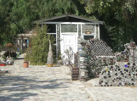 An outdoor structure built with glass bottles and stone walls.