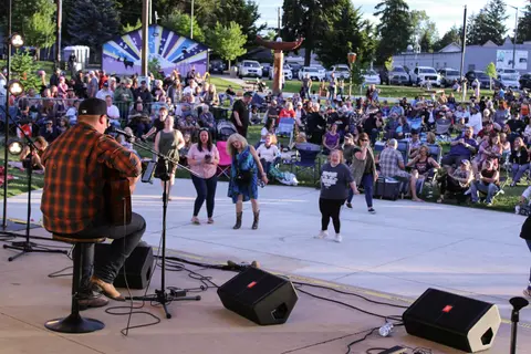 A musician performs with a guitar before an outdoor crowd.