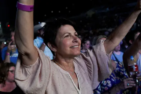 A woman with her arms raised in a crowd.