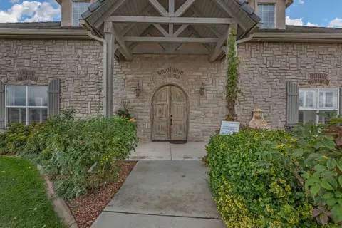 Exterior view of a stone building with arched wooden double doors and a covered entryway.