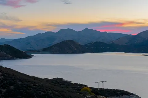 A scenic view of a lake surrounded by mountains at sunset.