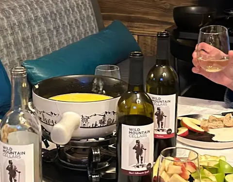 A fondue pot and wine bottles on a dining table.