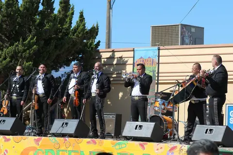 A mariachi band performs outdoors on a stage.