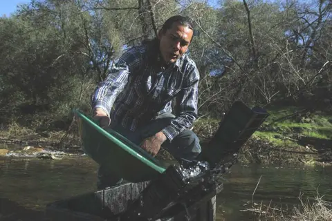 A person panning for gold in a stream.