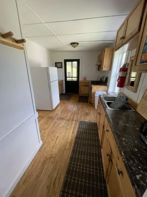 A bright rustic kitchen interior with wooden floors and cabinets.