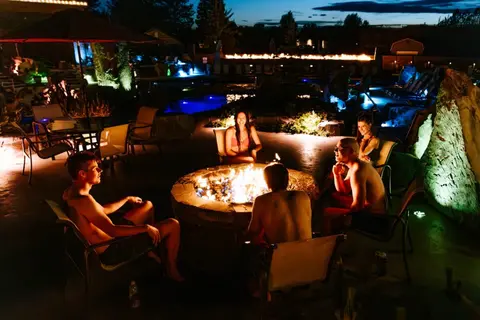 People sitting around a fire pit outdoors at night.