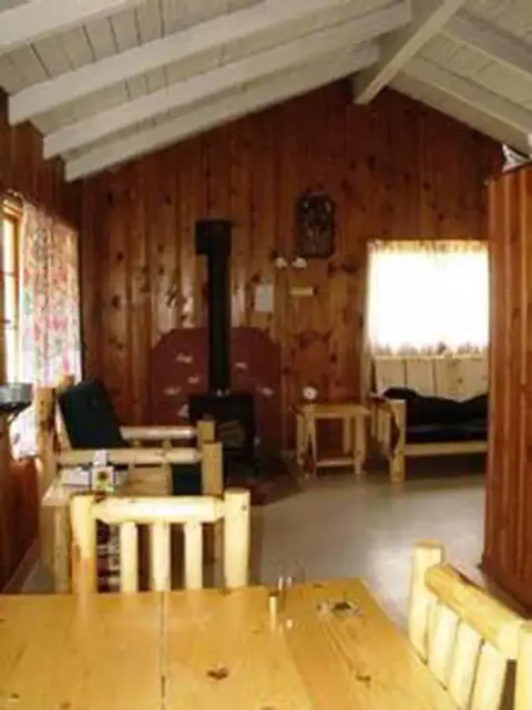 An interior view of a rustic wooden cabin with a stove and log furniture.