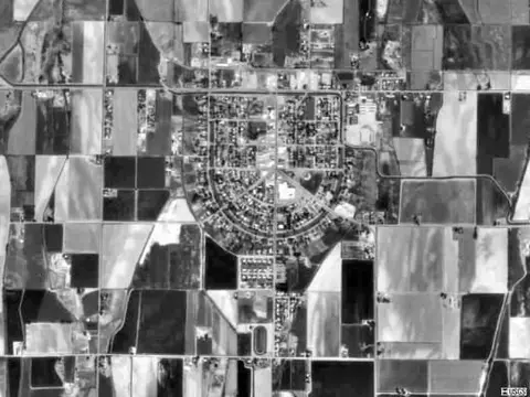 An aerial black-and-white photograph shows a circular town layout surrounded by fields.