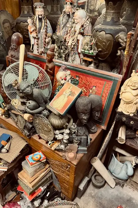 A cluttered display of antiques and curiosities including statues, figures, and various decorative items.