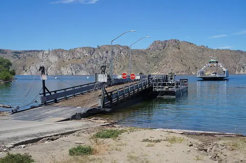 A floating dock on a lake with a ferry approaching in the background.