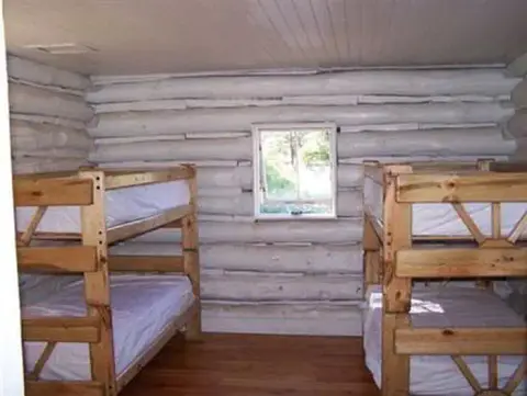 A small log cabin room furnished with two wooden bunk beds.