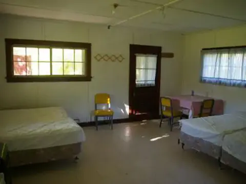 The interior of a room with multiple beds and chairs.