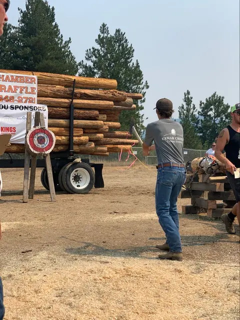 A man throws an axe at a target during an outdoor lumberjack competition.