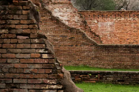 A photo showing weathered brick ruins with patches of grass.