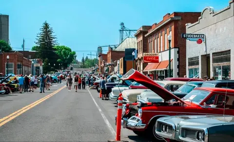 A classic car show lines the main street of a historic town.