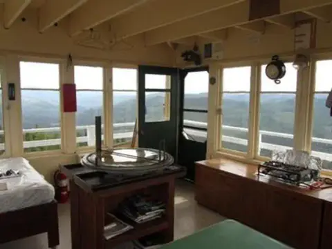 The interior of a fire lookout tower with windows looking out over a landscape.