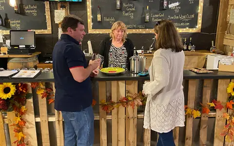 Customers are standing at a bar talking to the person behind the counter.