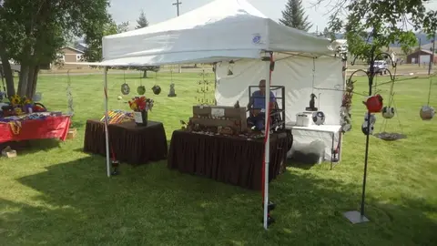 A white canopy tent set up on a grassy lawn with display tables.