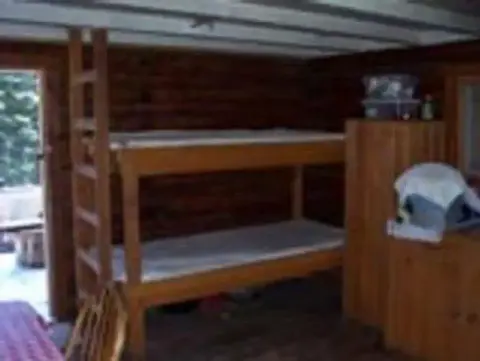 Interior view of a rustic room with bunk beds and wooden walls.