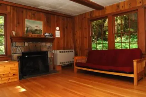 An interior room with wood paneling, a fireplace, and a red couch.