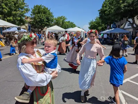 People in traditional attire gather at an outdoor street event.