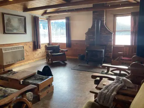 A rustic interior room with a stone fireplace and wooden furniture.