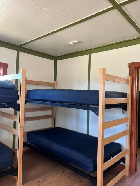 An interior view of a room with wooden bunk beds and blue mattresses.