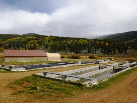 An outdoor fish hatchery with concrete raceways and buildings in a valley.