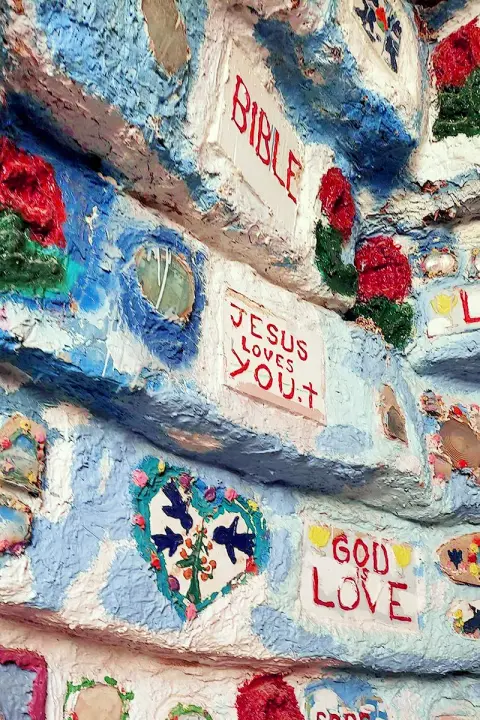 A close-up view of a brightly painted wall adorned with religious inscriptions and floral designs.