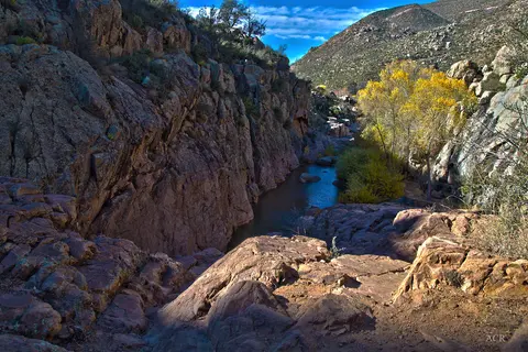A river flows through a rocky canyon with yellow trees.