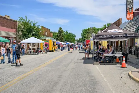 A street scene showing a crowd event with booths and tents lining the road.