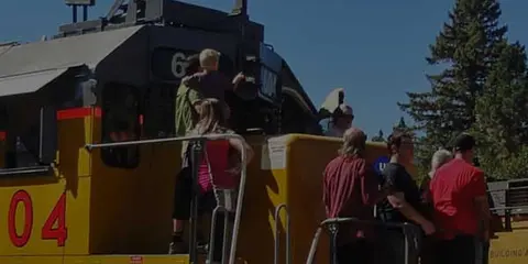 People stand near the front of a large train engine outdoors.