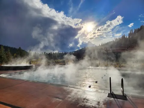 Steam rises from outdoor hot springs pools under a cloudy sky.