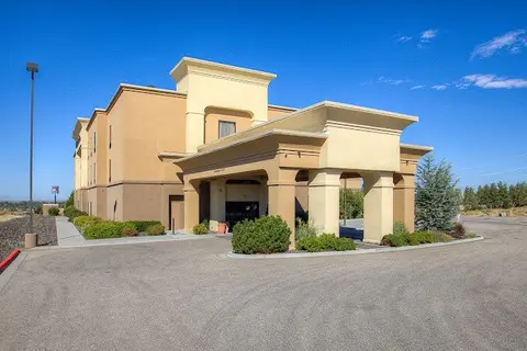 Exterior view of a modern hotel building with a covered entryway and a clear blue sky.