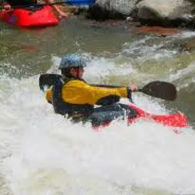 A person kayaking in a river with rapids.