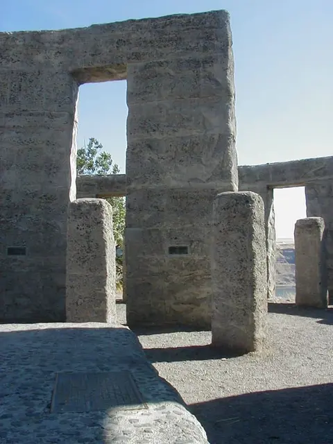 A stone structure resembling Stonehenge stands under a blue sky.