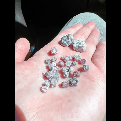 A person's hand holding several rough stones.