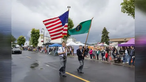 Two men carry flags in an outdoor parade.