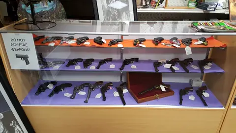 A display case filled with various handguns inside a shop.