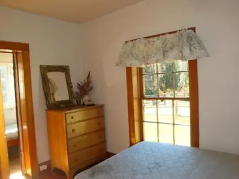 An interior view of a bedroom with a wooden dresser and a window.