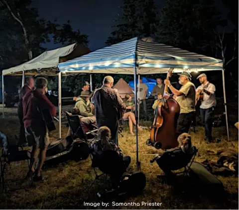 People playing music under tents at night outdoors.