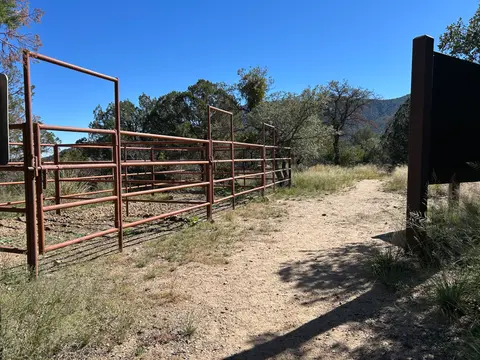 A dirt path leads past metal corrals under a clear blue sky.