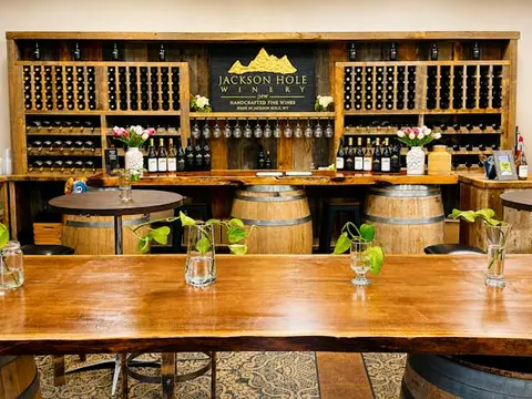 A wine tasting room featuring wooden wine racks, barrels, and tables.