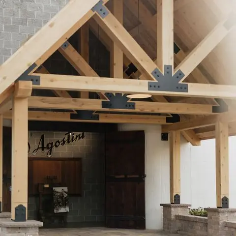 An exterior view of a wooden timber frame portico with metal brackets.