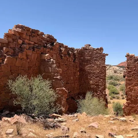 Ancient stone ruins stand against a clear blue sky.