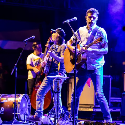 A band performing on stage with guitars and a microphone.