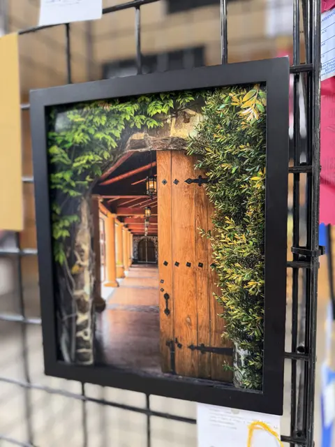 A framed photograph shows a wooden door opening into a covered hallway with greenery around the entrance.