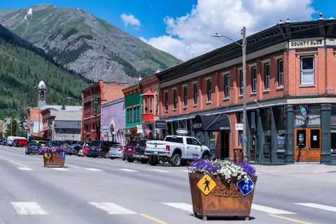 A street view of historic buildings with mountains in the background.