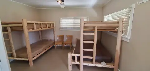 An interior bedroom with wooden bunk beds and chairs.