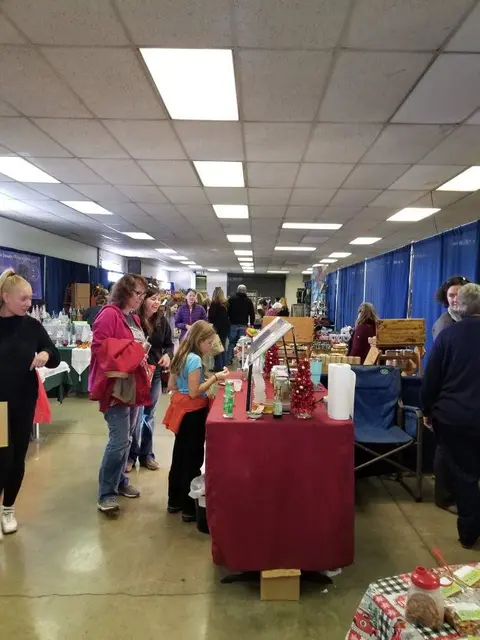 People browsing tables at an indoor craft fair or market.